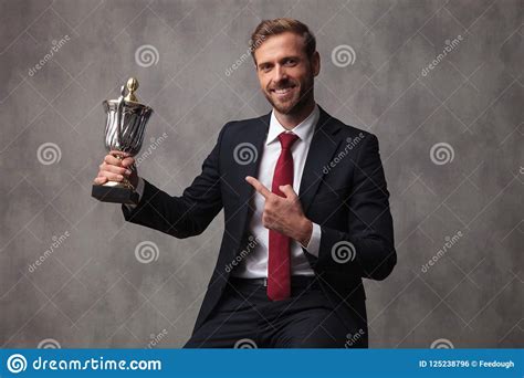 Happy Young Businessman Poiting To His Trophy And Smiles Stock Photo