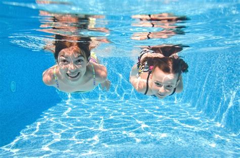 Дети плавают в бассейне под водой маленькие активные девочки веселятся