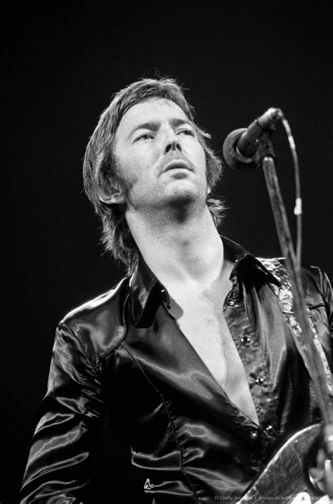 A Man Holding A Guitar While Standing In Front Of A Microphone With His