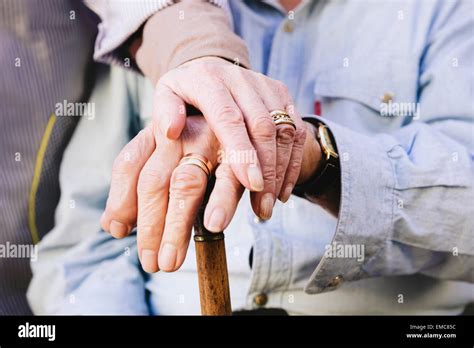 Close Up Of Old Mans And Womans Hands Resting On A Cane Stock Photo