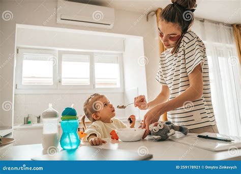 Padre Femenino Dando Comida A Su Hija En La Cocina Imagen De Archivo