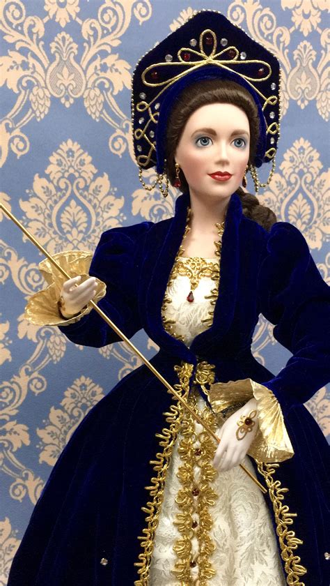 A Doll Dressed In Blue And Gold Holding A Wand With Her Hands Standing
