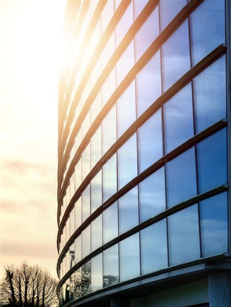 Facade Of Modern Glass Building And Round Shape At Sunset Clouds