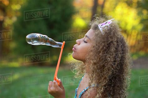 Mixed Race Girl Blowing Bubbles Outdoors Stock Photo Dissolve