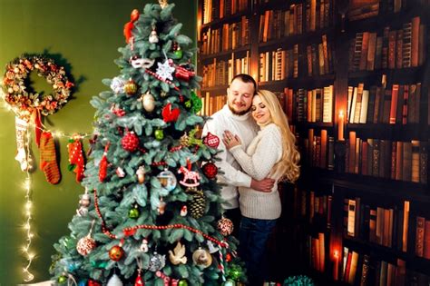Abrazo De Pareja Se Encuentra Delante De Un árbol De Navidad Foto Gratis