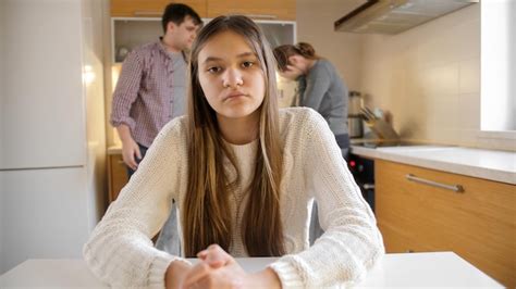 Девочка подросток смотрит в камеру пока родители спорят и конфликтуют на кухне Премиум Фото