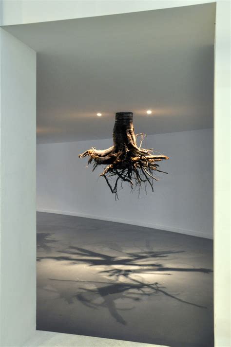 tree roots emerge from the ceiling in an installation by giuseppe licari
