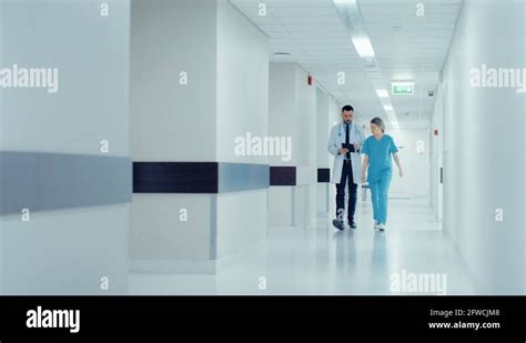 Surgeon And Female Doctor Walk Through Hospital Hallway Stock Video