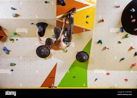 Young Man Climbing Challenging Bouldering Route In Indoor Climbing Gym