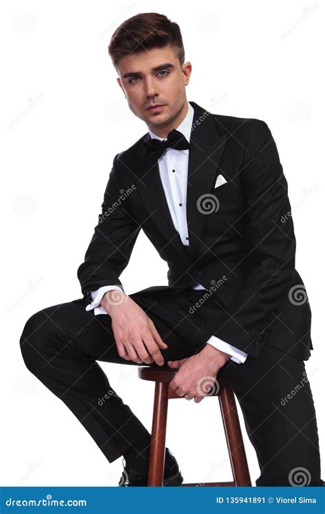 Young Businessman In Black Tuxedo Sitting On Wooden Chair Stock Image