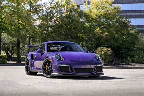 A Purple Sports Car Parked In Front Of Some Trees