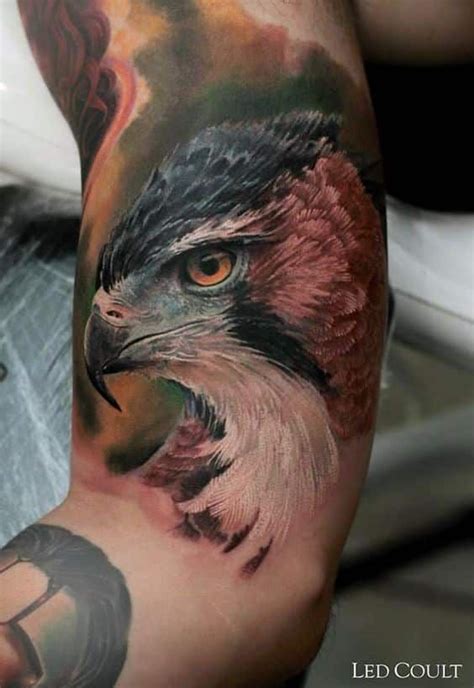 The Arm With An Eagle Tattoo On It Is Painted Red Orange And Green Colors