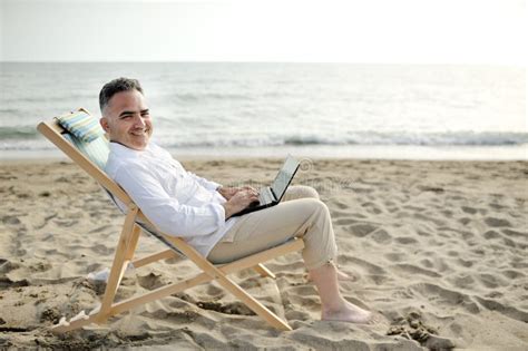 Man With Laptop Working On The Beach Sitting On A Deckchair Stock Image