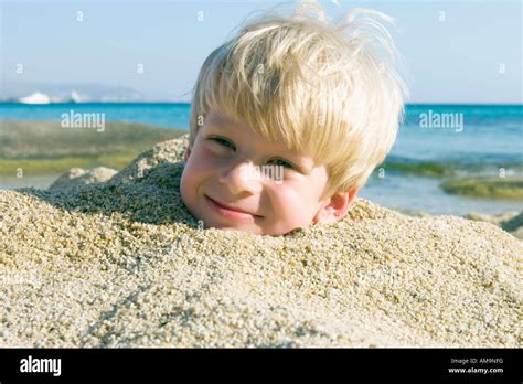 Young Boy Buried In The Sand Smiling Stock Photo Alamy