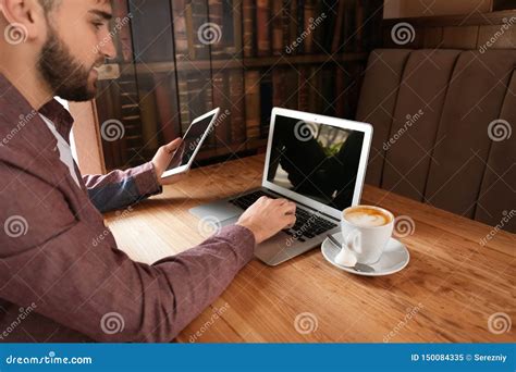 Young Freelancer With Tablet Pc And Laptop Working In Cafe Stock Image
