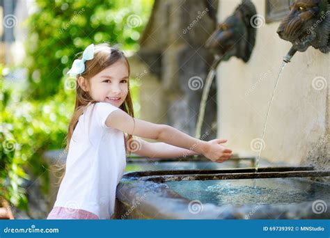 Adorable Little Girl Playing With A Drinking Water Fountain Stock Photo