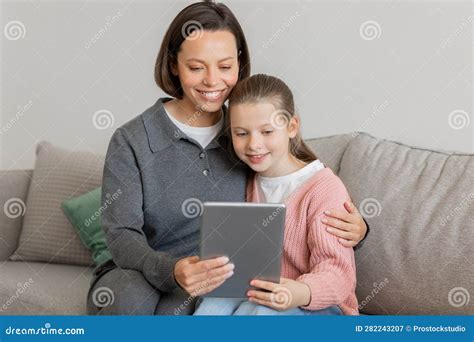 Glad Millennial Caucasian Woman Hugging Teen Daughter Have Video Call Read Message On Tablet