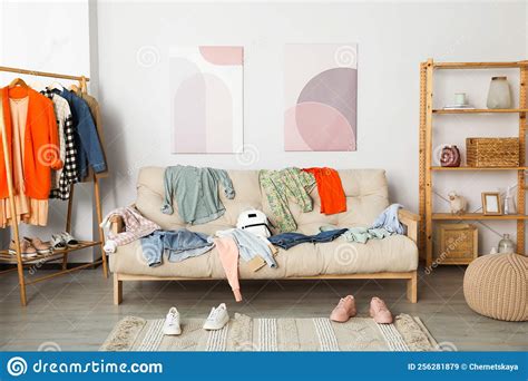 Messy Pile Of Clothes On Sofa And Shoes In Living Room Stock Image