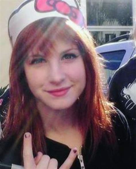 a woman with red hair wearing a hello kitty hat and holding up her peace sign