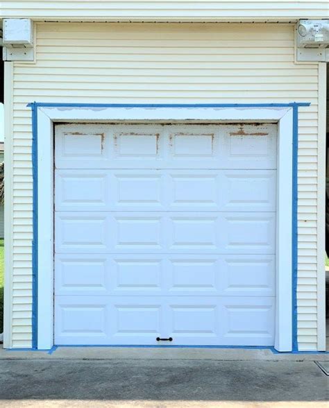 A White Garage With Blue Trim On The Side And An Open Door That Is Closed