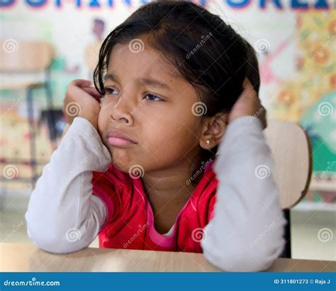 Portrait of a Young Asian Girl Sadly Sitting at Desk in School Stock