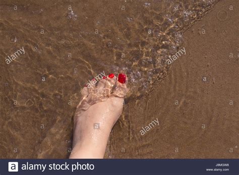 Beach Scene With Woman Feet On The Sand Nails Of Feet Painted Red