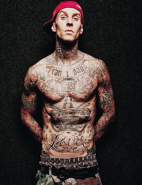 A Man With Lots Of Tattoos On His Body And Chest Standing In Front Of A