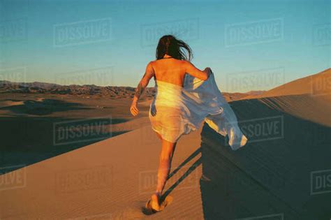 Naked Female Wrapped In White Cloth Walking On A Sand Dune Stock Photo Dissolve