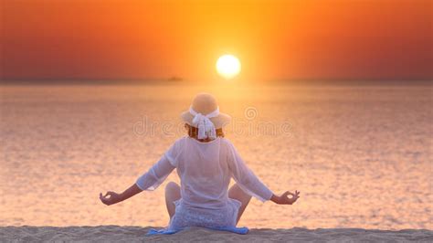 Woman Meditating In Yoga Pose On The Beach At Beautiful