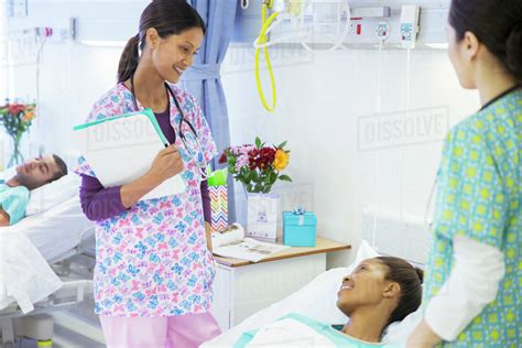 Smiling Nurses Talking With Patient In Hospital Room Stock Photo
