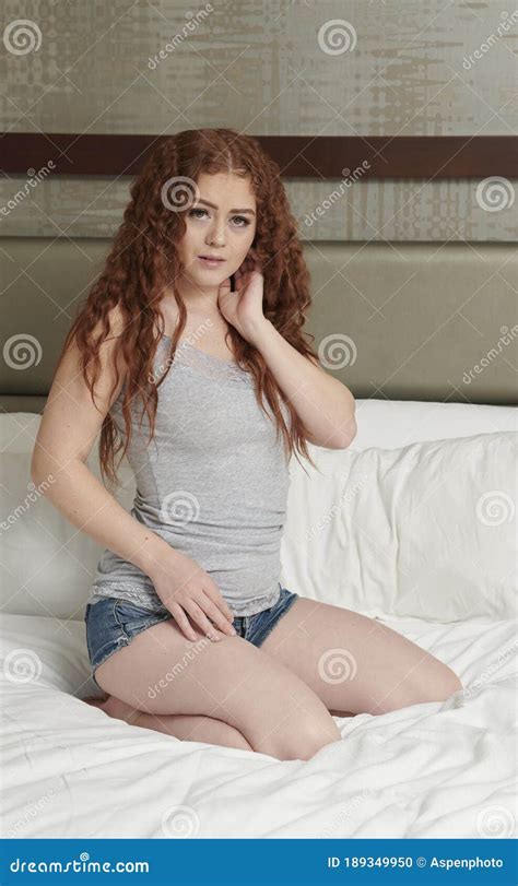 Young Redhead Woman In Bed Wearing Grey Tank Topn And Denim Shorts