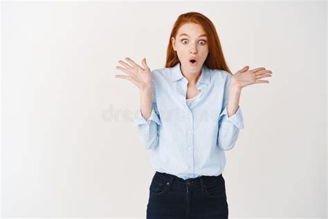 Surprised Redhead Woman Looking Down With Hands Spread Sideways In