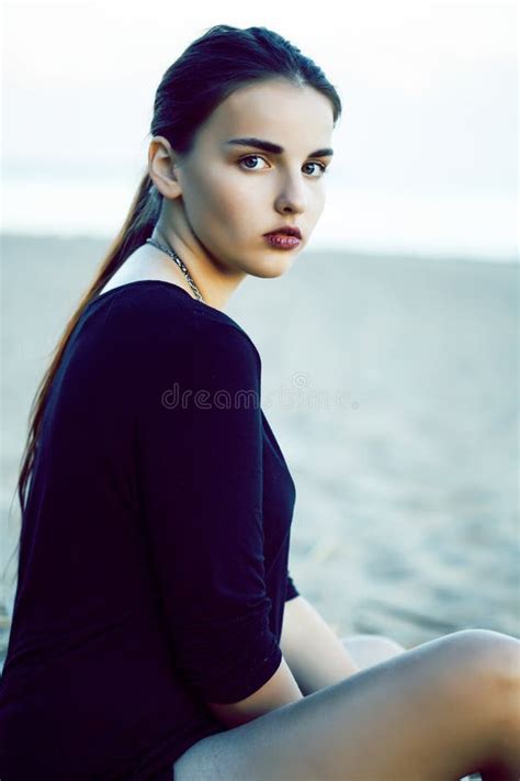 Young Pretty Brunette Girl With Long Hair Waiting Alone On Sand At