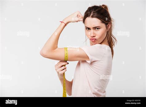 Portrait Of A Confident Fit Girl Flexing Biceps With A Measuring Tape