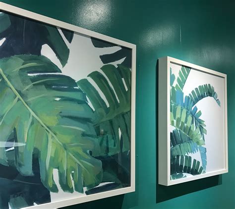 Two Paintings Hanging On The Wall Next To Each Other With Green Leaves