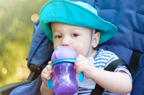 Baby Drinks From Bottle And Sitting In A Baby Carriage Stock Photo