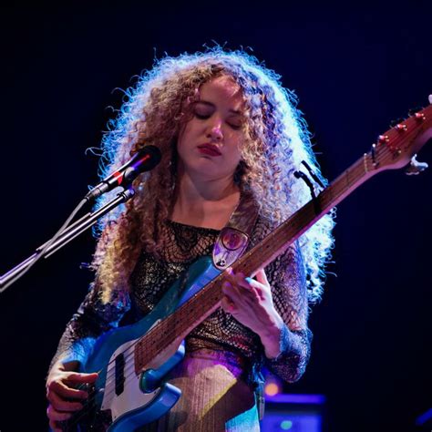 A Woman With Curly Hair Playing An Electric Guitar At A Music Concert