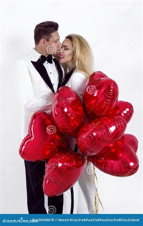 Beaux Couples Heureux Posant Sur Le Fond Blanc Et Tenant Le Coeur De Ballons Jour Du `s De