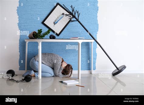 Young Woman Hiding Under Table During Earthquake Stock Photo Alamy