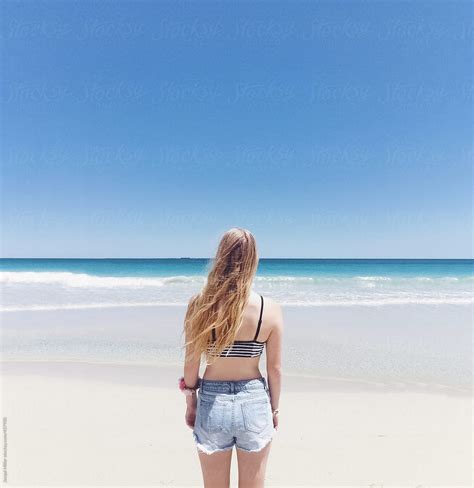 Back View Of Young Woman With Long Blonde Hair Facing The Ocean Del