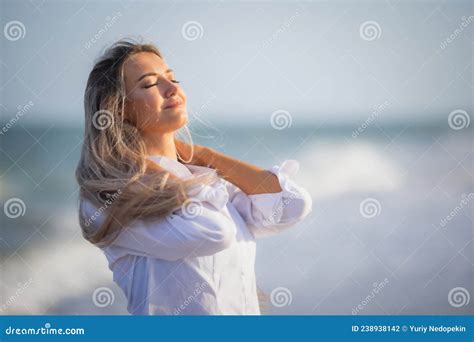 A Tanned Girl In A Blue Swimsuit And A Light Shirt Enjoys The Summer At