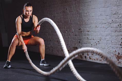 Athletic Woman Doing Battle Rope Exercises At Gym Premium Photo