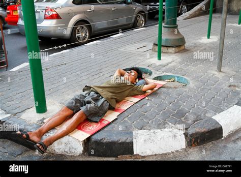 Homeless Man Sleeping On A Sidewalk In Bangkok Thailand Stock Photo