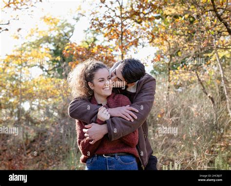 Young Man Kissing Girlfriend In Autumn Forest Stock Photo Alamy