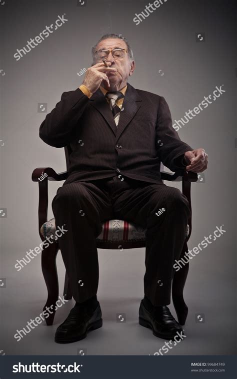 Old Man Sitting In A Chair And Smoking A Cigarette Stock Photo 99684749