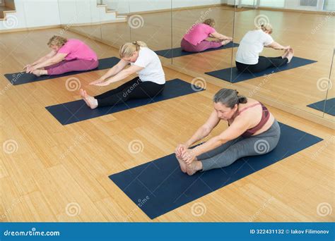 Women Practicing Yoga Sitting In Seated Forward Bend Exercise