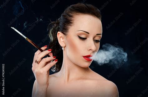Woman With Red Lips Blowing The Smoke On Black Background Stock Photo