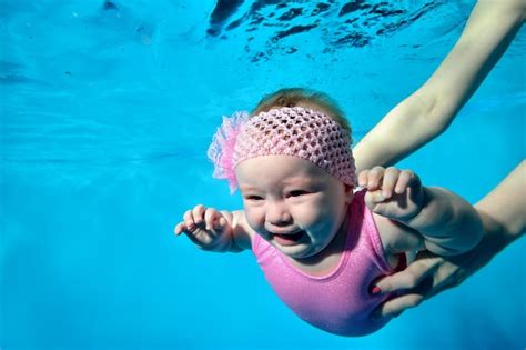Un Bebé Llorando En Brazos De Su Madre Bajo El Agua En La Piscina
