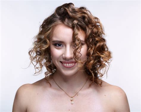 Portrait Of Young Smiling Woman With Curly Hair On Gray Background