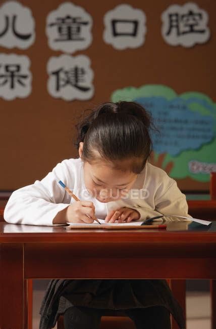Schoolgirl Writing In Workbook At Class — Black Hair Chinese Ethnicity